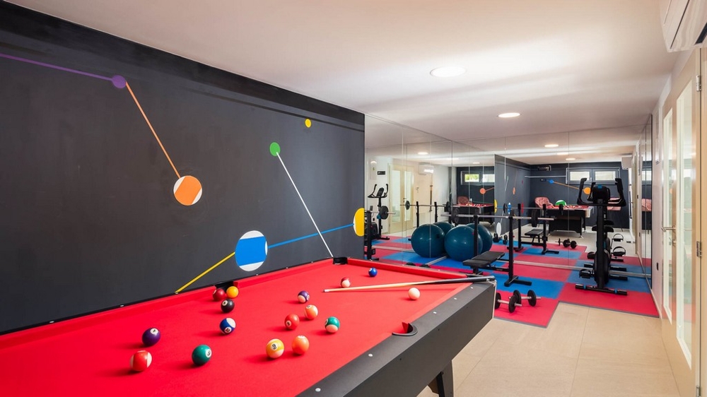 Sala per il tempo libero e fitness con tavolo da biliardo e attrezzi per l'allenamento