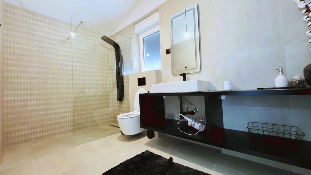 Bagno con doccia a filo pavimento e lavabo moderno