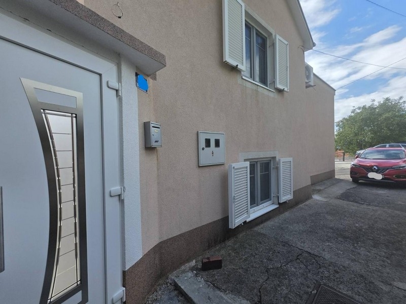 Facciata della casa con porta d'ingresso, persiane e posto auto