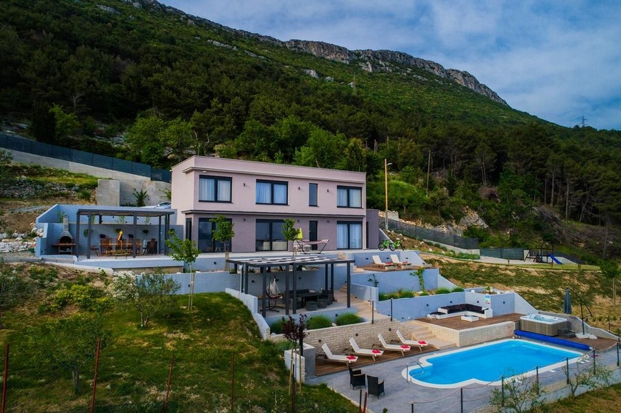 Casa rosa con piscina e vasca idromassaggio davanti alla montagna