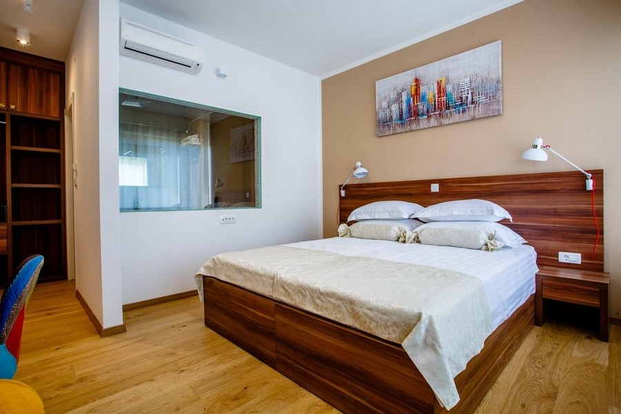 Camera da letto luminosa con letto matrimoniale e pavimento in legno