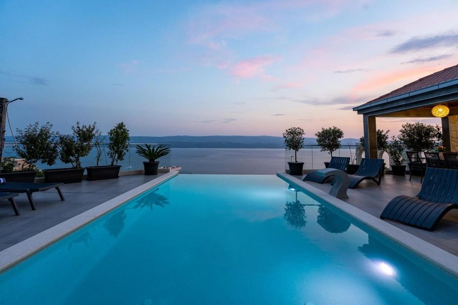 Piscina al tramonto con vasi di piante e lettini