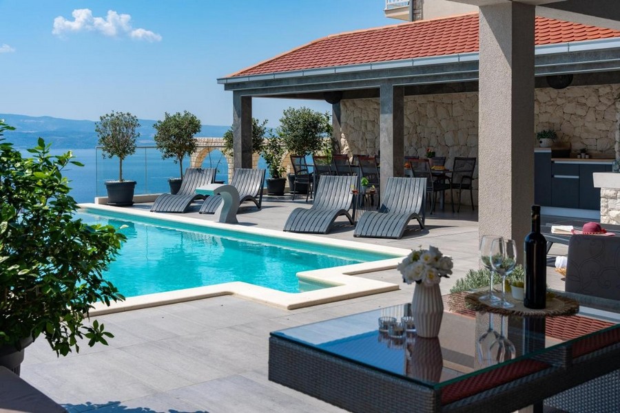 Terrazza della piscina con lettini prendisole e zona pranzo coperta