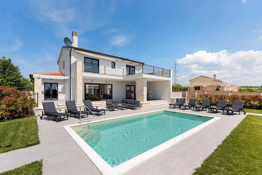 Villa con basamento in pietra naturale e piscina con fila di lettini