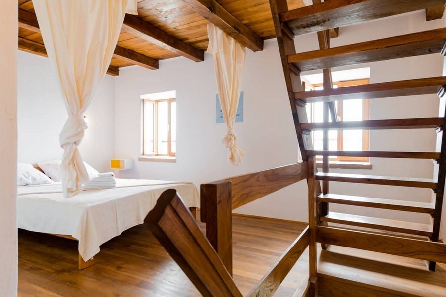 Camera da letto con pavimento in legno, scala e luce naturale