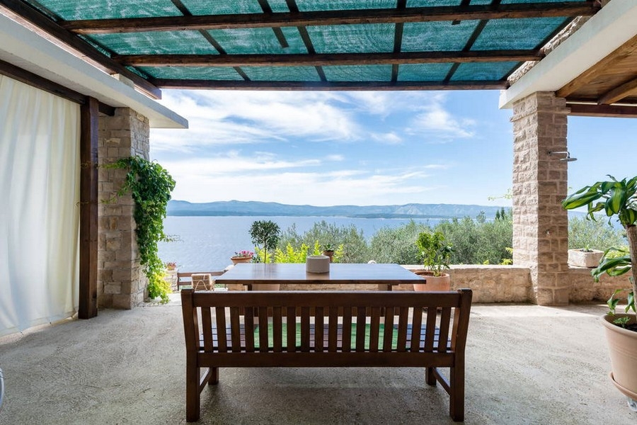 Terrazza coperta con tavolo in legno e vista mare