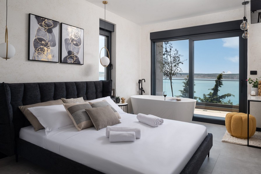 Camera da letto con letto matrimoniale, vasca da bagno freestanding e vista mare