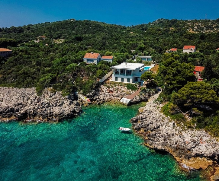 Villa bianca sopra la baia rocciosa con acqua turchese