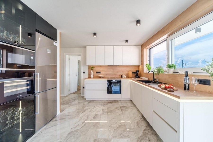 Cucina a incasso luminosa con elettrodomestici moderni e piastrelle in marmo