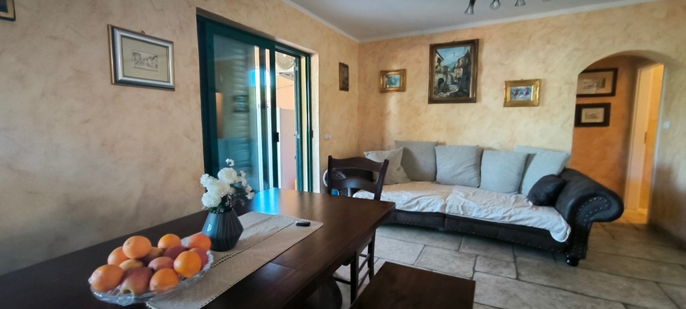 Zona giorno con divano, tavolo e accesso alla terrazza