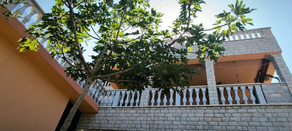 Facciata della casa con balcone e albero in primo piano