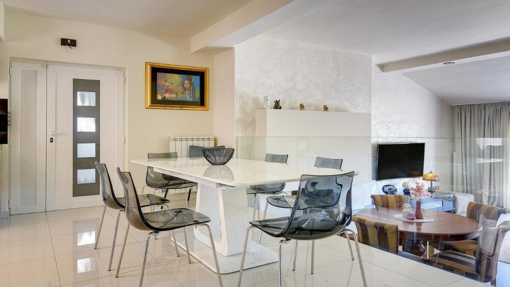 Zona pranzo moderna con tavolo bianco e parapetto in vetro