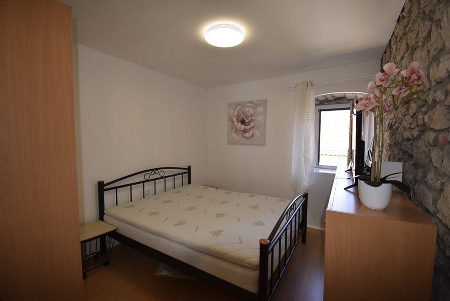 Camera da letto luminosa con letto matrimoniale e parete in pietra