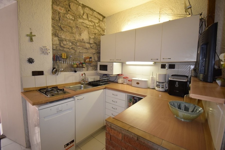 Cucina con blocco cucina componibile e parete in pietra