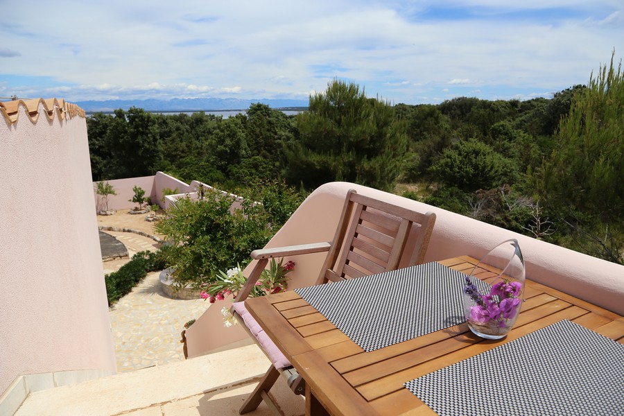 Terrazza con tavolo in legno e sedie, vista sul verde e sul mare