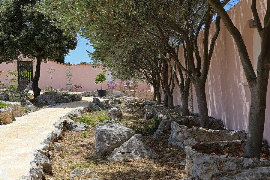 Vialetto del giardino con alberi e pietre naturali accanto alla casa