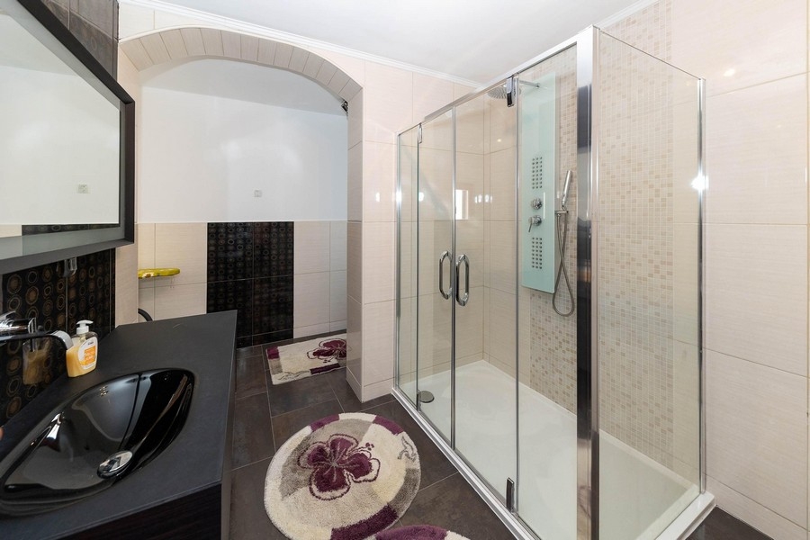 Bagno moderno con grande doccia in vetro e lavabo scuro