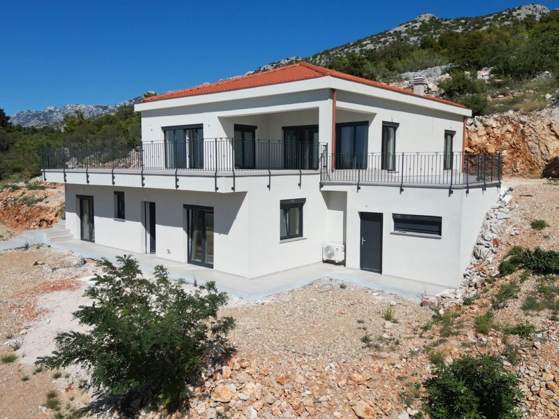 Casa bianca con balcone perimetrale davanti alla parete rocciosa