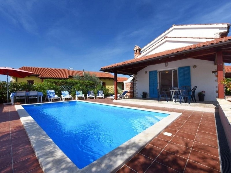 Piscina con persiane blu sulla casa e ombrellone