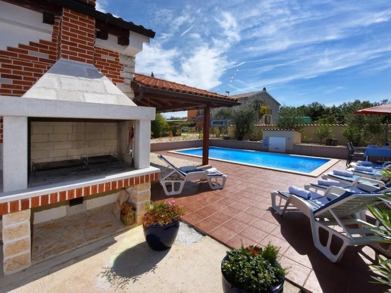 Zona barbecue con vista sulla piscina e sulla terrazza solarium della casa.