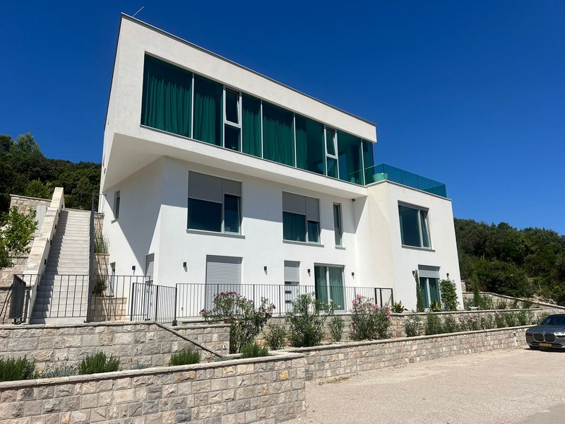 Casa bianca con parapetti in vetro verdi sopra il muretto a secco