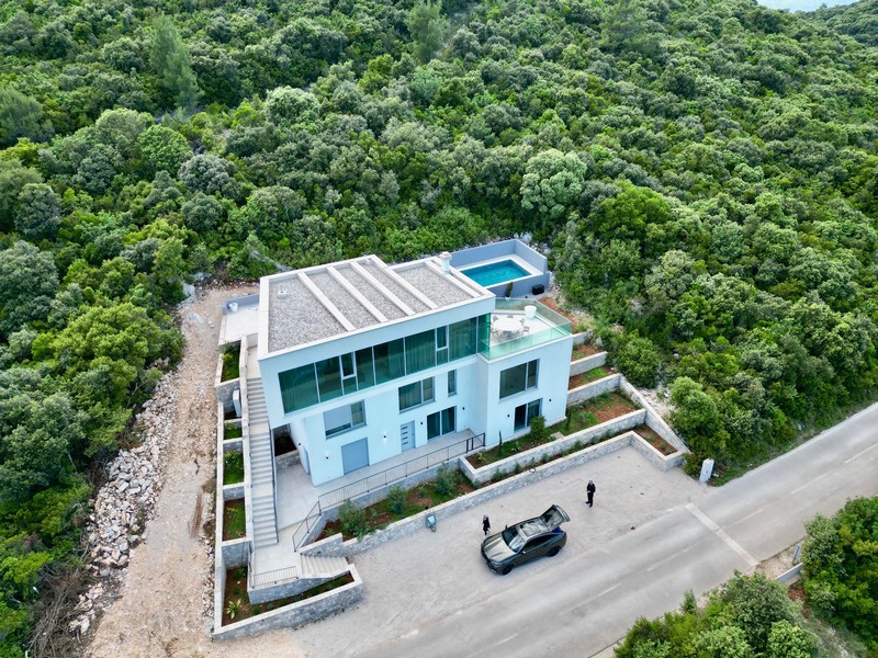 Vista aerea della villa con piscina sul tetto tra pendii boscosi