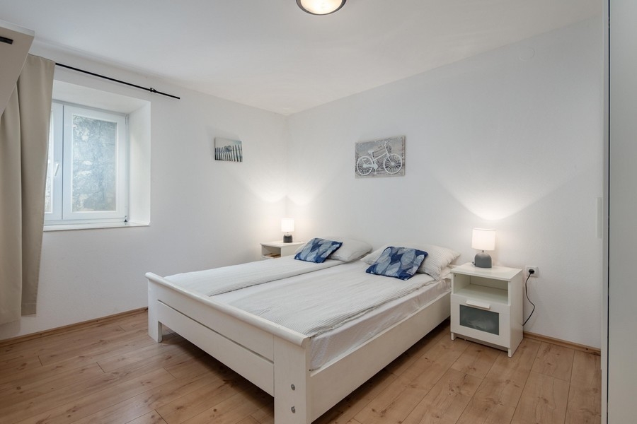 Camera da letto luminosa con letto matrimoniale e pavimento in legno