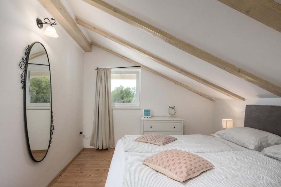Accogliente camera da letto nel sottotetto con travi in legno