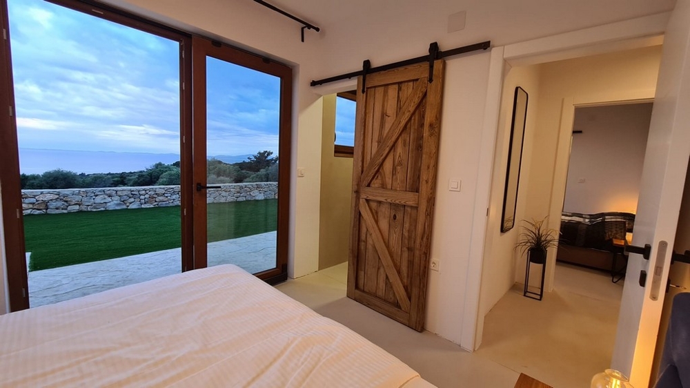 Camera da letto con porta scorrevole in legno e vista sul prato
