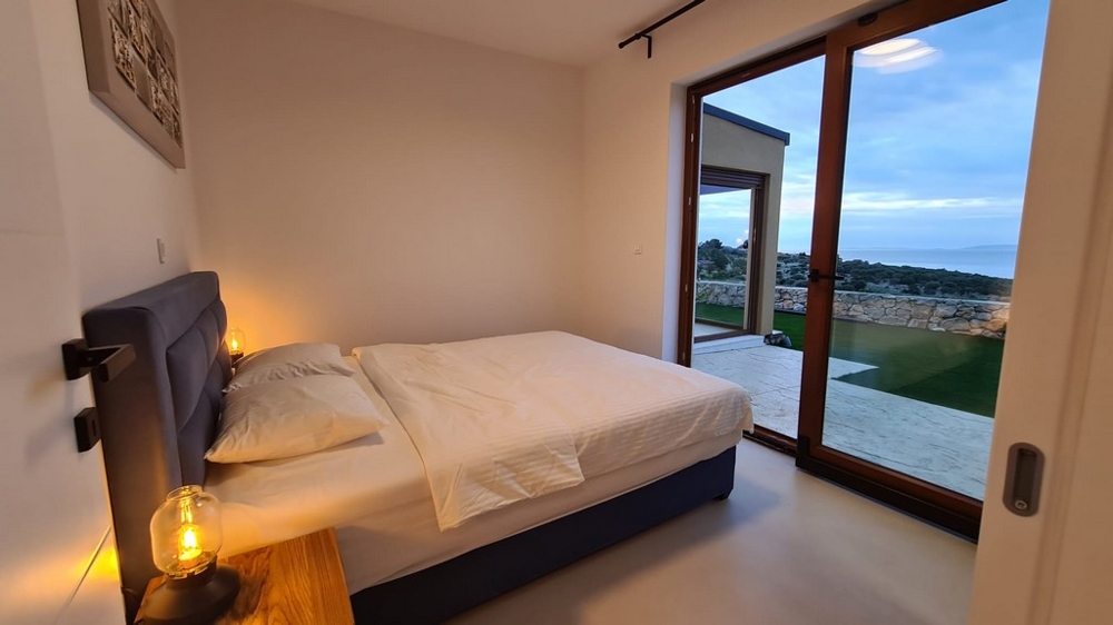 Letto alla finestra a tutta altezza con luce della sera sul mare