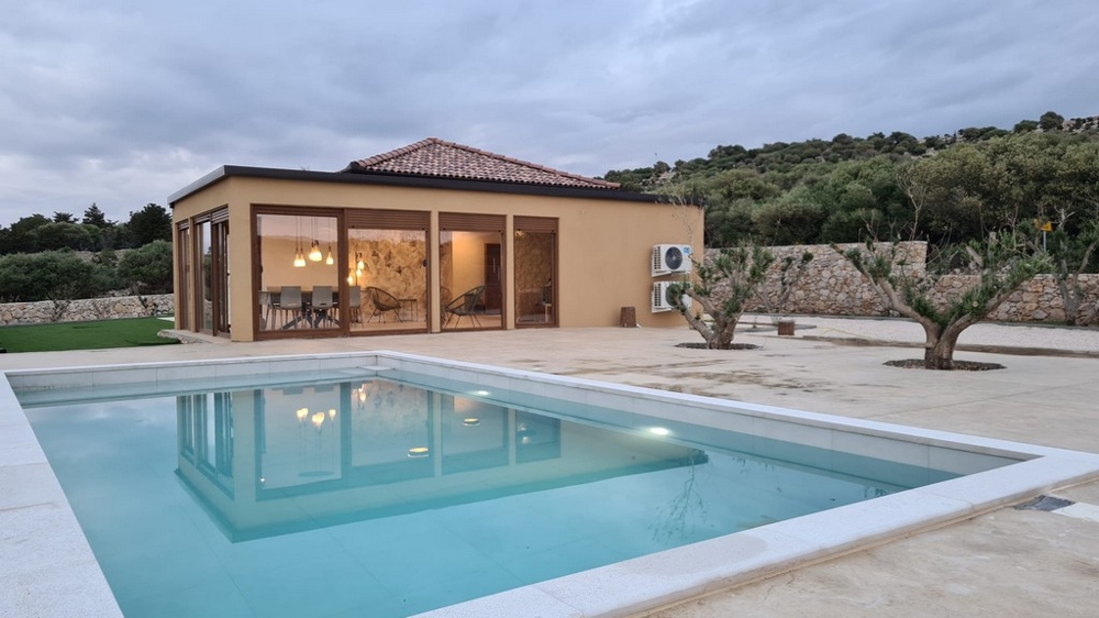 Piscina davanti alla casa con grande vetrata la sera