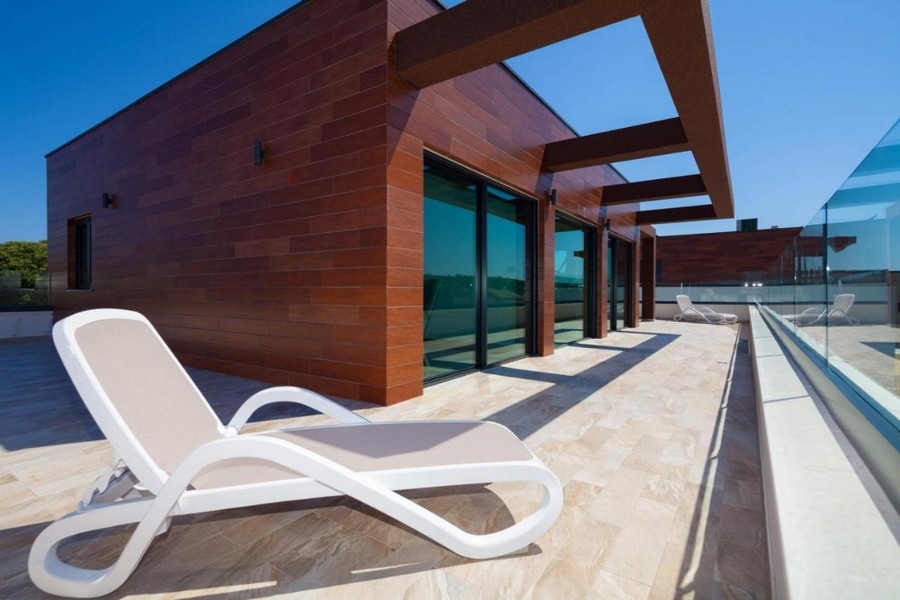 Terrazza sul tetto con lettino davanti alla facciata in legno e alla pergola