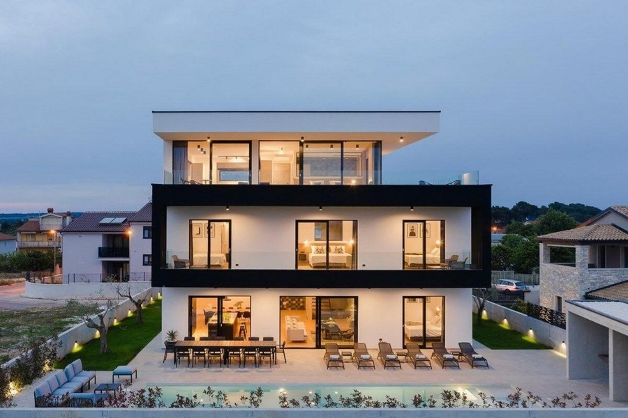 Villa illuminata su tre piani con piscina al crepuscolo