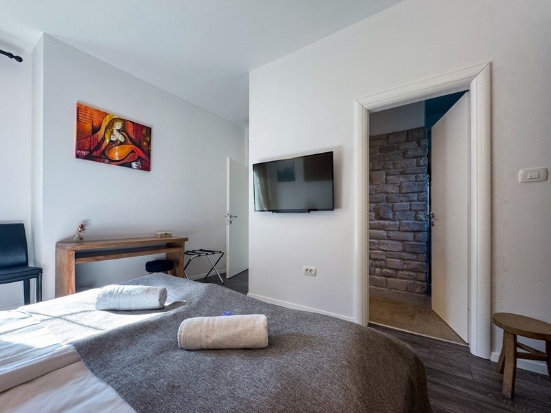 Camera da letto luminosa con TV e dettagli in pietra alla parete