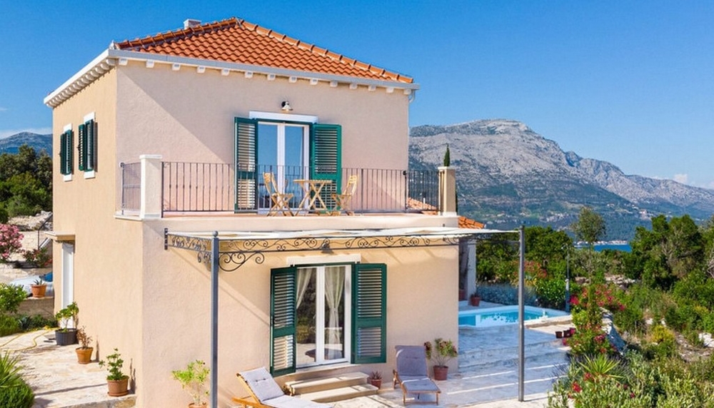 Casa con persiane verdi e balcone davanti alla catena montuosa