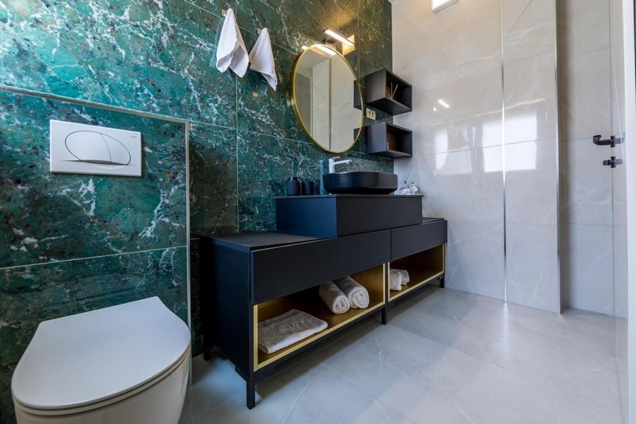 Bagno con parete in marmo verde e lavabo moderno