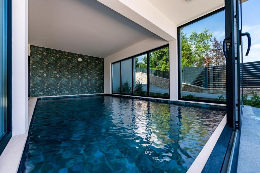 Piscina interna con grande vetrata e vista sul giardino