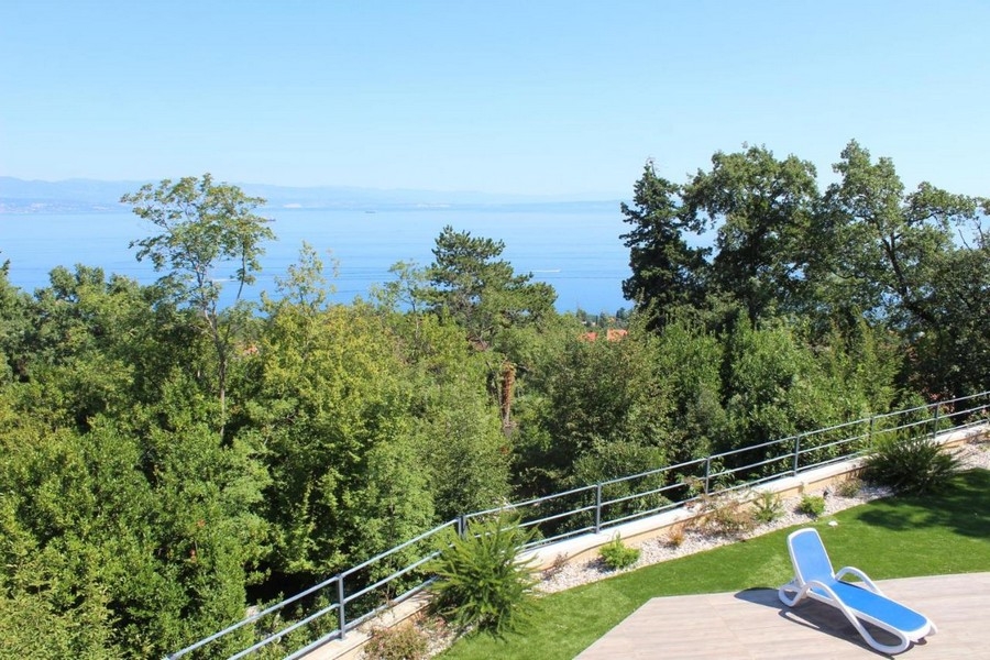 Lettino sul prato con vista sulle chiome degli alberi fino al mare