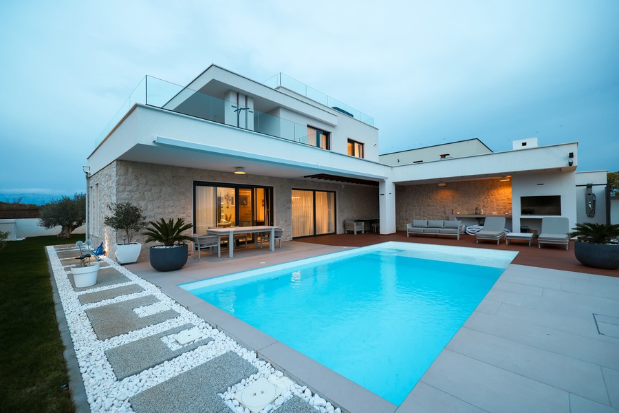 Villa illuminata con piscina e fascia di ghiaia al crepuscolo