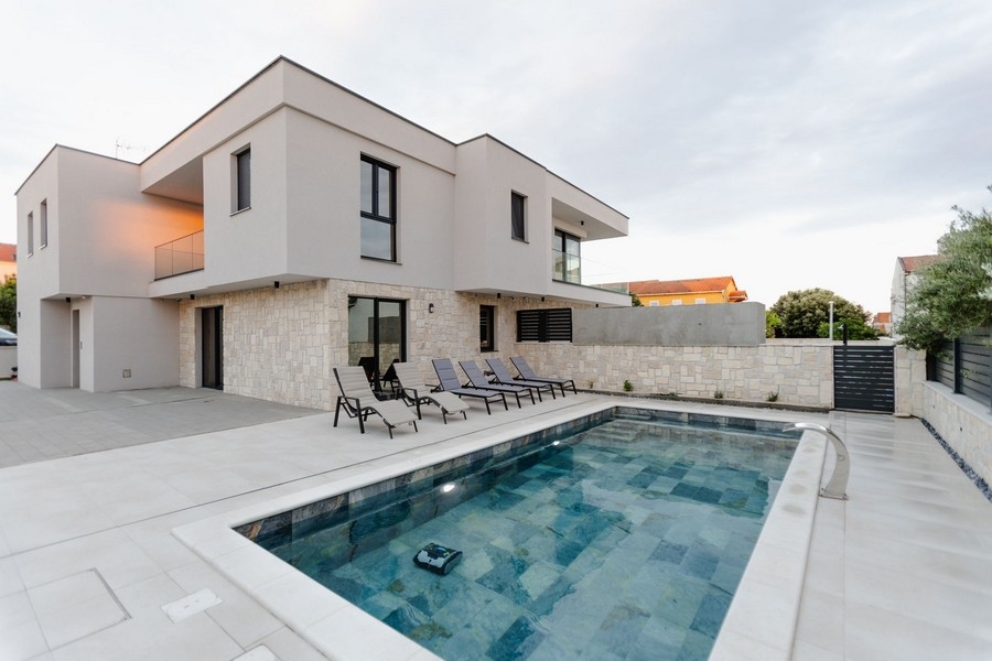 Casa bifamiliare con zoccolo in pietra naturale e piscina con lettini