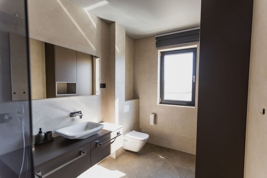 Bagno con lavabo d'appoggio e WC sospeso in tonalità beige