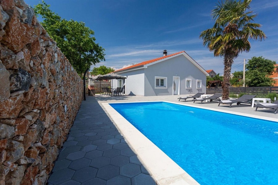 Piscina con palma e lettini al muro in pietra naturale