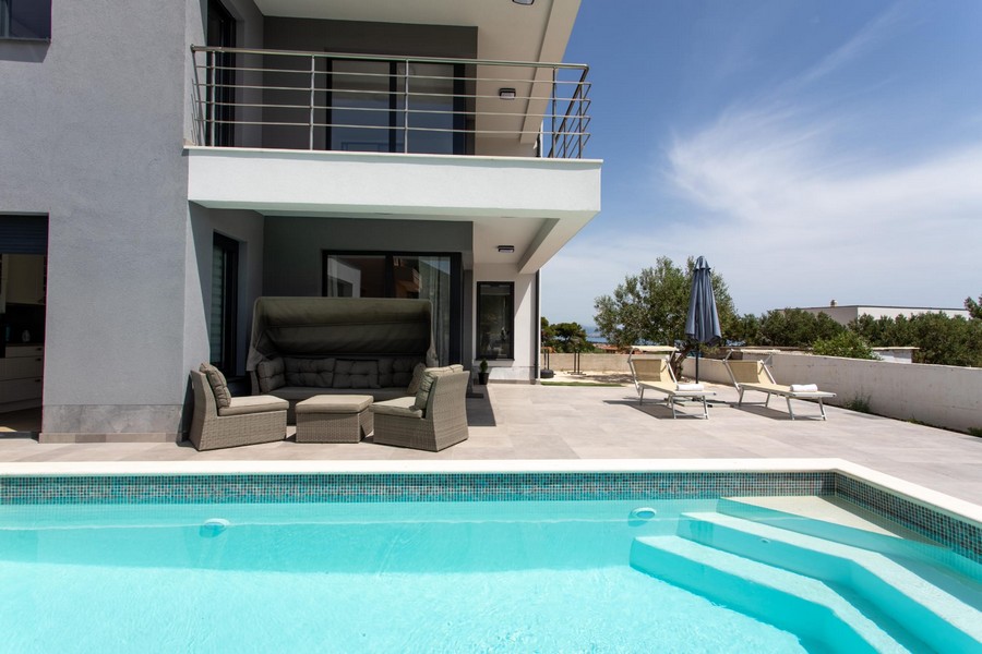 Terrazza della piscina con lounge sotto il balcone della villa