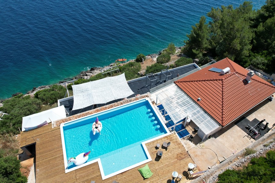 Piscina con tenda parasole e piattaforma in legno sopra l'acqua