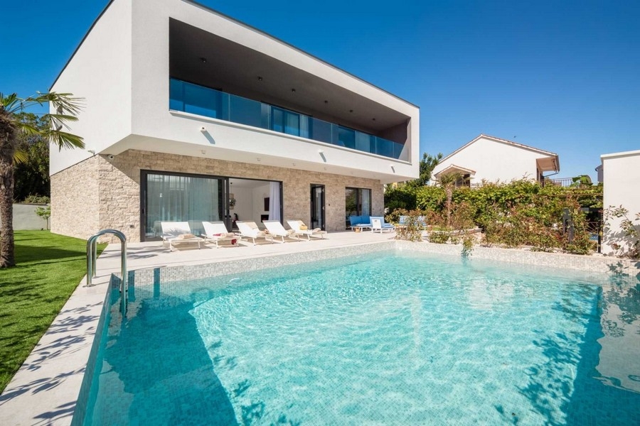 Villa luminosa con zoccolo in pietra e lunga piscina davanti