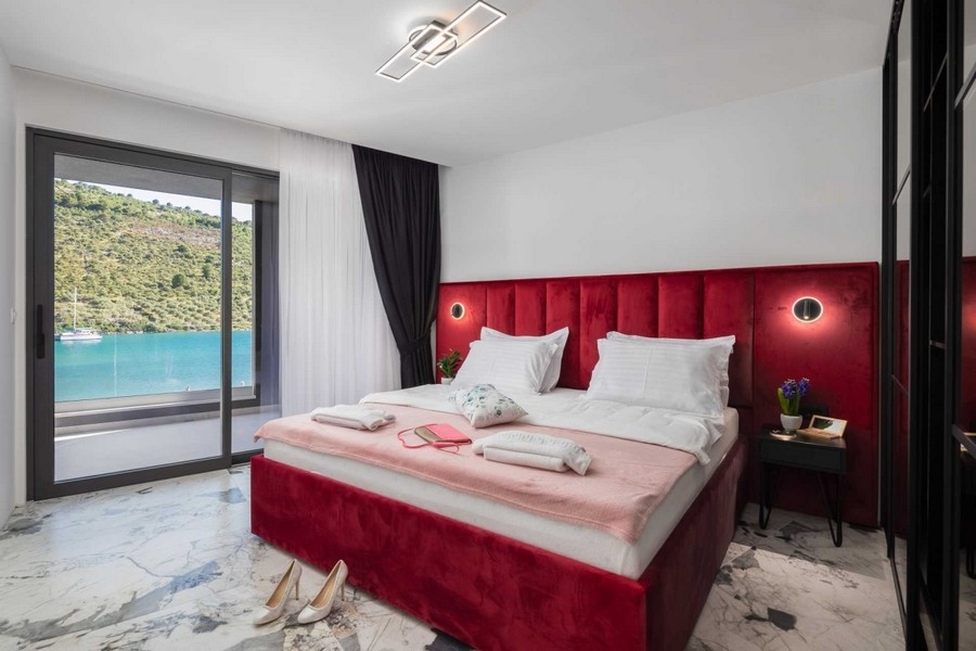 Camera da letto con letto imbottito rosso e vista mare