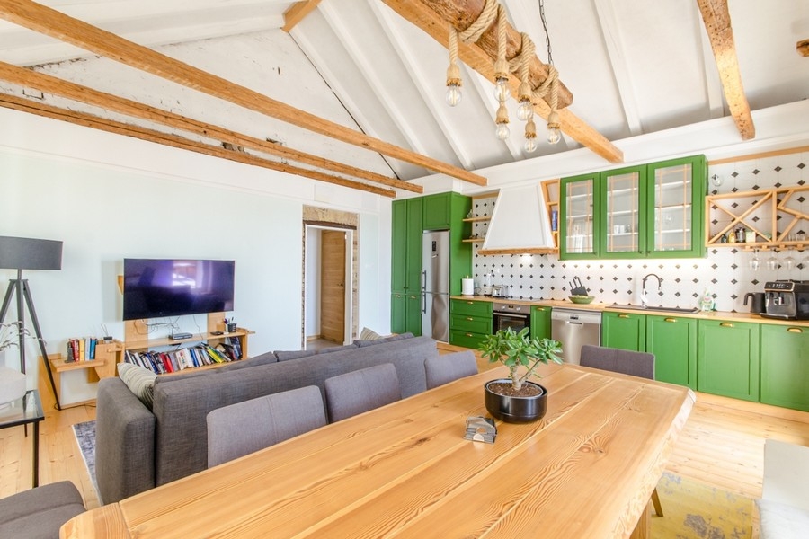 Zona giorno con cucina aperta e soffitto a travi in legno