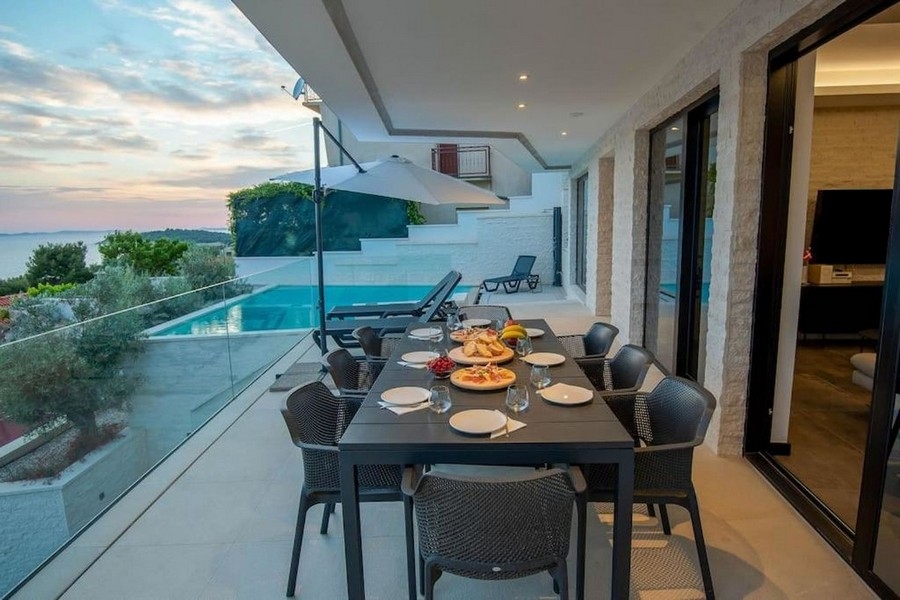 Terrazza con tavolo da pranzo, vista mare e piscina a Primosten