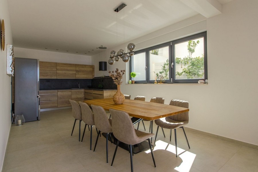 Zona pranzo con grande tavolo in legno e illuminazione moderna