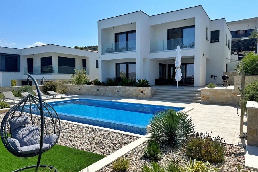 Villa con piscina e sedia sospesa nel giardino di ghiaia